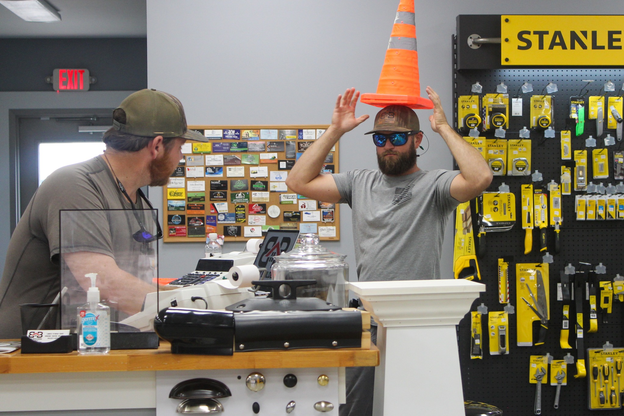 Two Best Builders Supply team members joking with a traffic cone at the counter