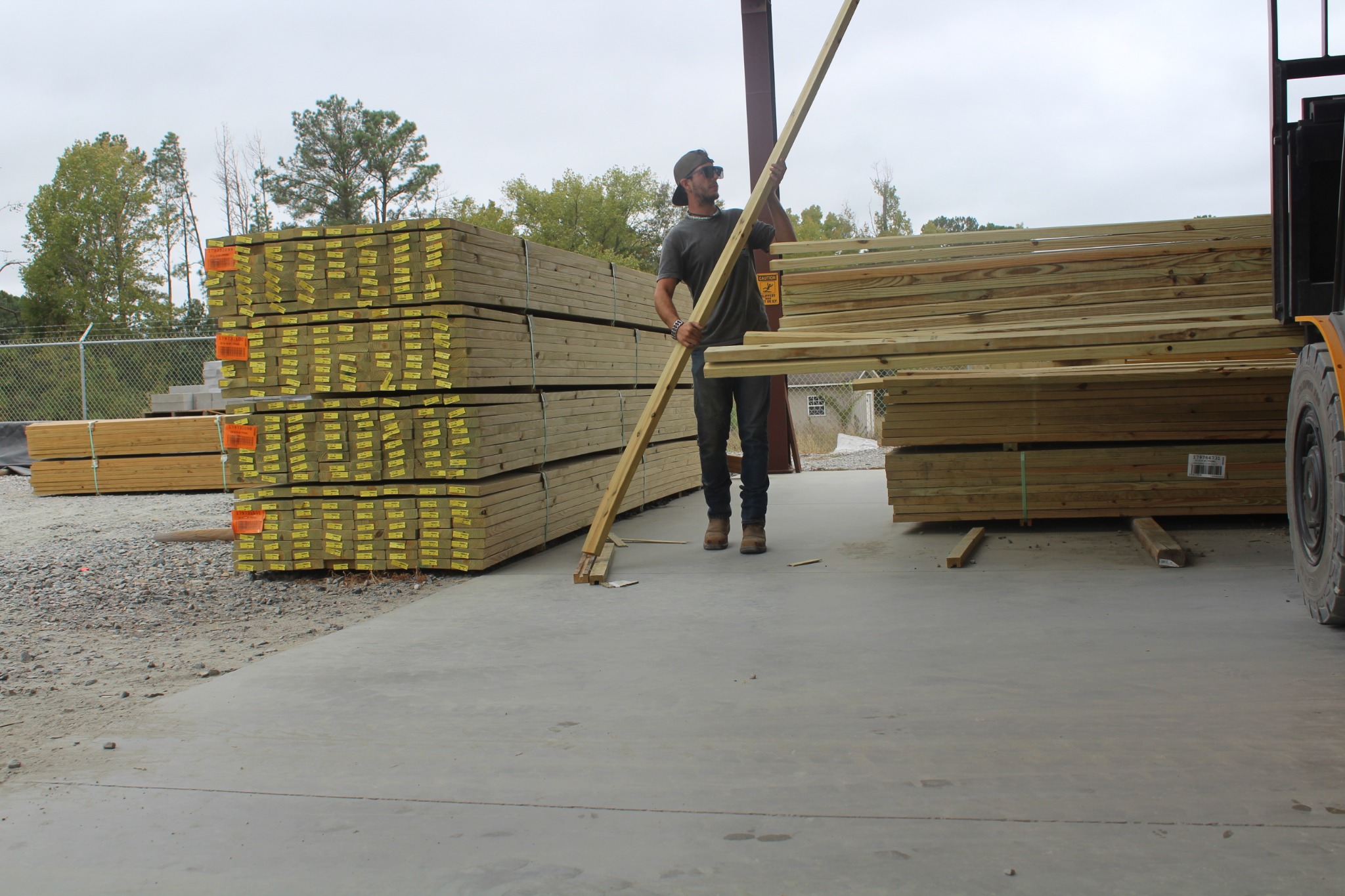 Chris carrying a long board through the Best Builders Supply yard